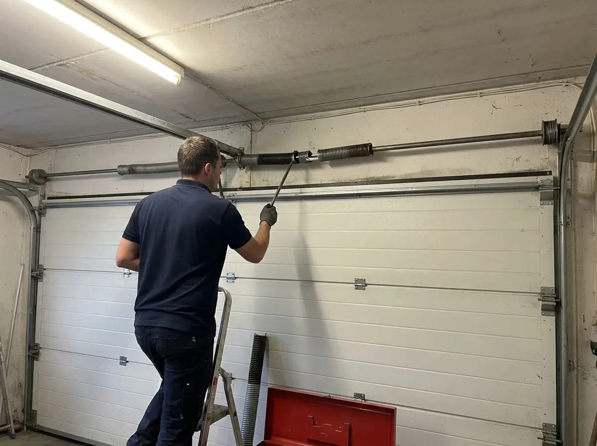 Technicien remplaçant un ressort de torsion au-dessus d’une porte de garage